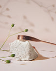 Copper ARISTA tongue scraper resting on a pale rock with delicate green stems in the background