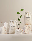 Two beige drawstring pouches with the arista logo displayed among rocks and copper tongue scrapers