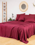 Bamboo Flat Sheets in burgundy drape over a bed in a cozy bedroom.