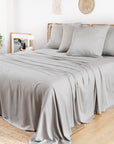 Bamboo Flat Sheets in light grey cover a bed in a bright, minimalist room.