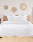 White bamboo duvet cover on a bed in a neutral bedroom with round wicker wall art