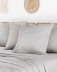 Beige bamboo pillowcases two-pack displayed on a light bed with woven wall decor.