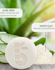 Shaving bar with aloe vera and white clay ingredient labels on a green blurred backdrop