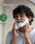 Close up of a person with shaving foam on their face during grooming