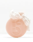 Shaving bar with foamy lather on top held in a hand against a white background