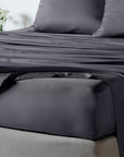 bambaw cozy bamboo bed sheets close up on a bed with fitted sheets and pillows in dark grey colour