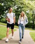 Two people walking on a path in a park holding bambaw reusable water bottles