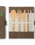 Open bamboo cutlery set in a brown fabric roll with spoon fork serrated knife and straw
