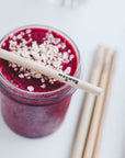 Purple smoothie in a jar with a bamboo straw across the rim