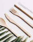 Flat lay of a natural bamboo cutlery set including spoon, fork, knife and chopsticks on a white surface