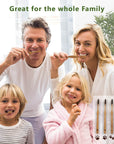 Smiling family of four brushing teeth with bamboo toothbrushes in a bright bathroom