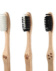 Three bamboo toothbrushes with white and black bristles arranged in a row