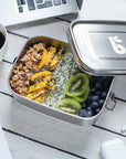 Stainless steel leakproof lunch box opened to show a meal with mango kiwi and granola