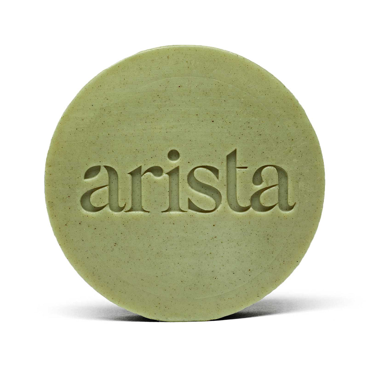 Close-up of pale green round arista shampoo bar with embossed lettering