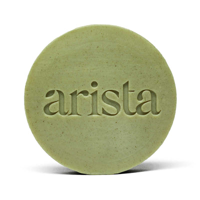 Close-up of pale green round arista shampoo bar with embossed lettering