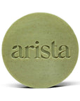Close-up of pale green round arista shampoo bar with embossed lettering