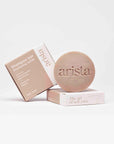 Shampoo bar packaging and a speckled round shampoo bar arranged together for curly hair care