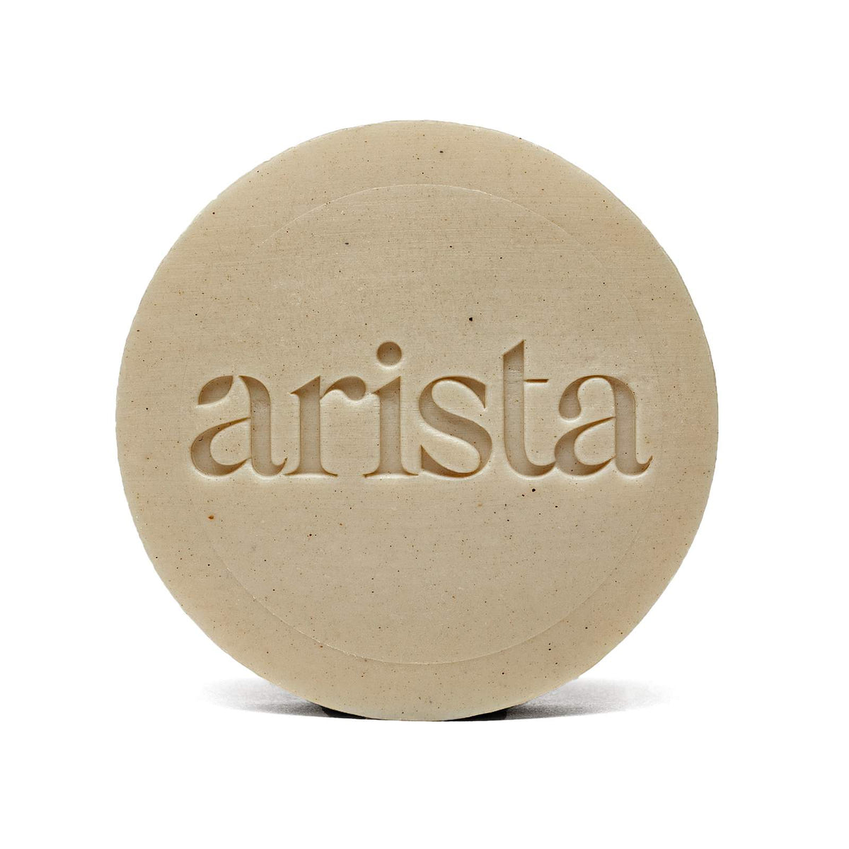 Beige round shampoo bar with arista embossed across the center.