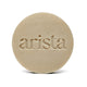 Beige round shampoo bar with arista embossed across the center.