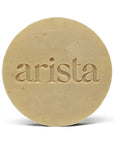 Beige circular shampoo bar for oily hair embossed with arista atop its orange packaging box
