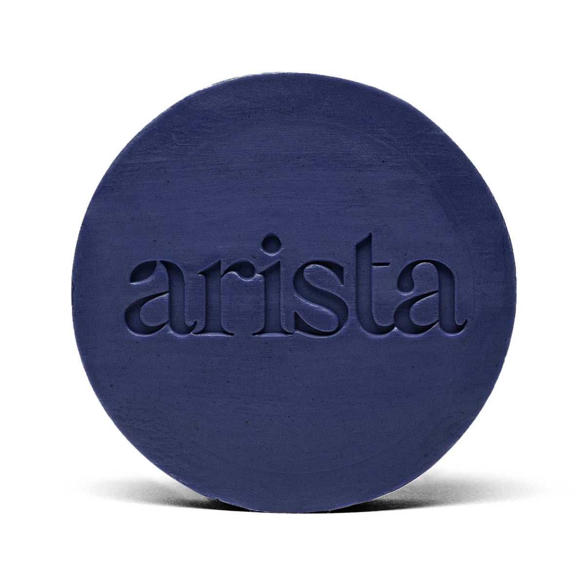 Deep blue circular shampoo bar with arista logo embossed on its surface