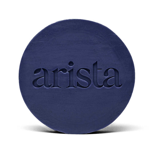 Deep blue circular shampoo bar with arista logo embossed on its surface