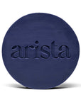 Deep blue circular shampoo bar with arista logo embossed on its surface