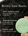 Close up of dark hair with a pale green circular shampoo bar held at the bottom right