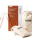 Copper tongue scrapers beside beige drawstring pouches and a brown packaging box in a product shot