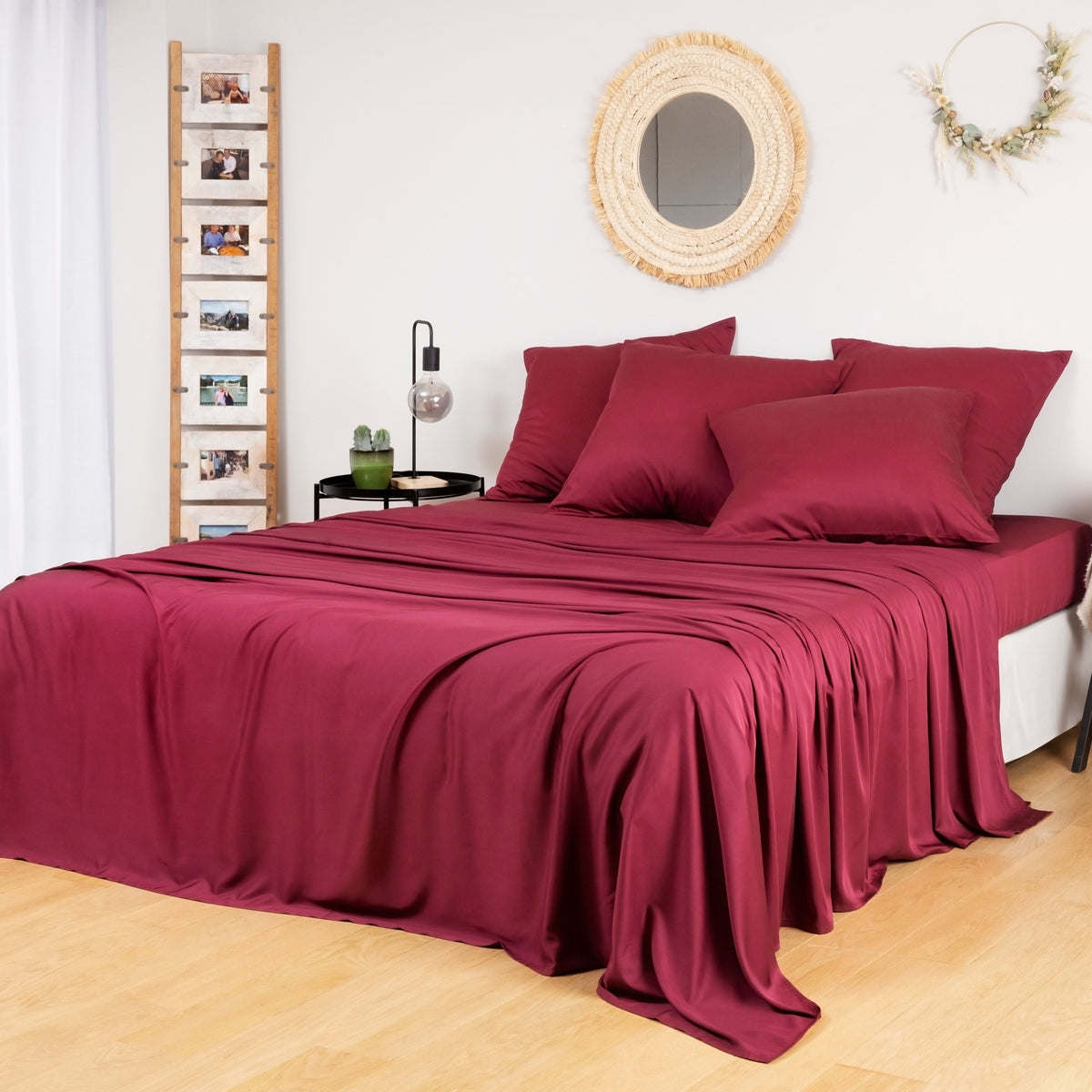 Bamboo Flat Sheets in burgundy drape over a bed in a cozy bedroom.