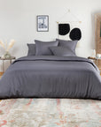 Bed dressed in a dark slate grey bamboo duvet cover with matching pillows in a minimalist bedroom.