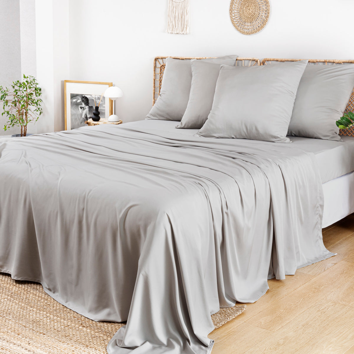 Bamboo Flat Sheets in light grey cover a bed in a bright, minimalist room.
