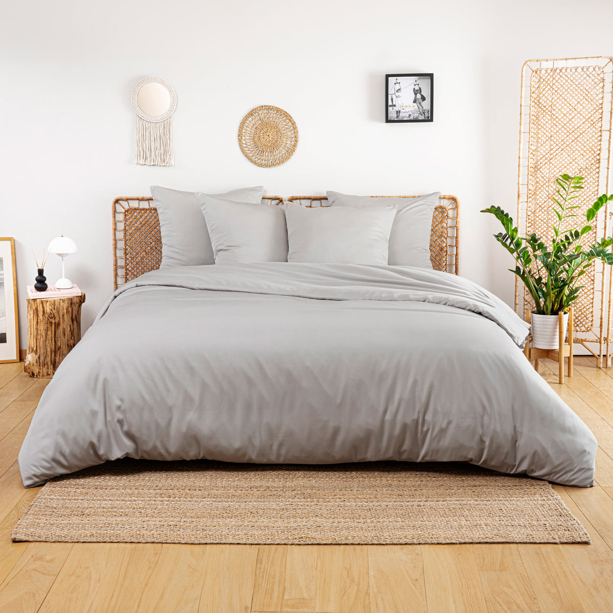 Bed dressed in a cool gray Bamboo Duvet Cover with gray pillows against a white wall and woven accents
