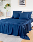 Navy blue Bamboo Flat Sheets on a bed with a white headboard in a bright room