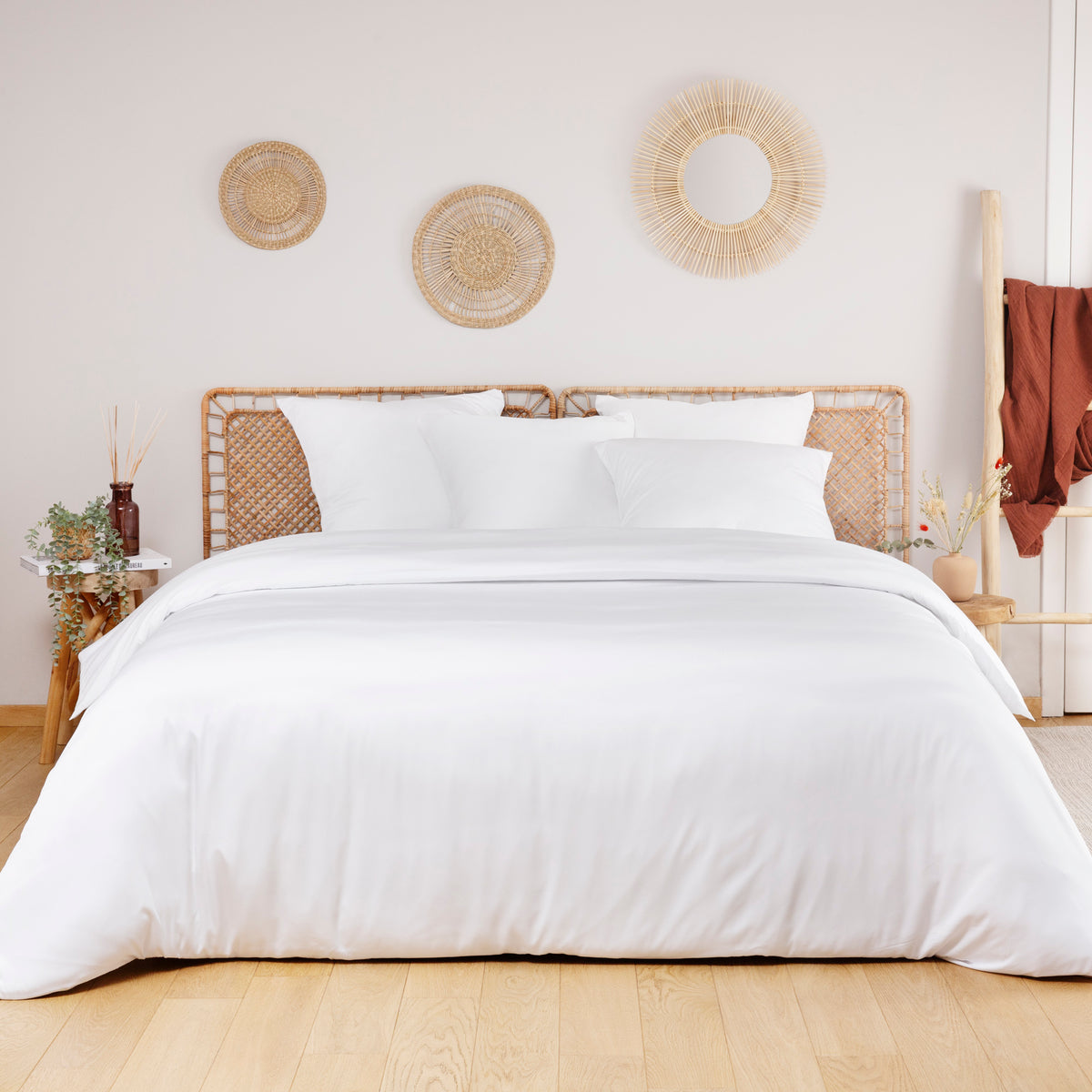 White bamboo duvet cover on a bed in a neutral bedroom with round wicker wall art