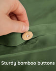 Hand pressing a wooden button on a green fabric with text 'Sturdy bamboo buttons'.
