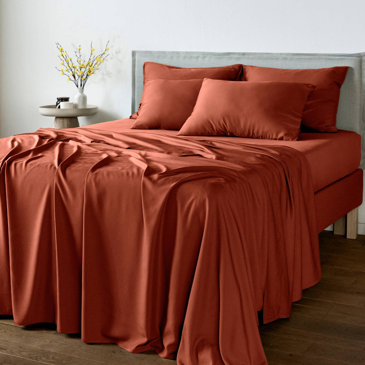 Bed with bambaw cozy terracotta bedding set and pillows in a room setting.