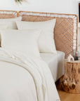 White pillows arranged on a bed with a woven wicker headboard