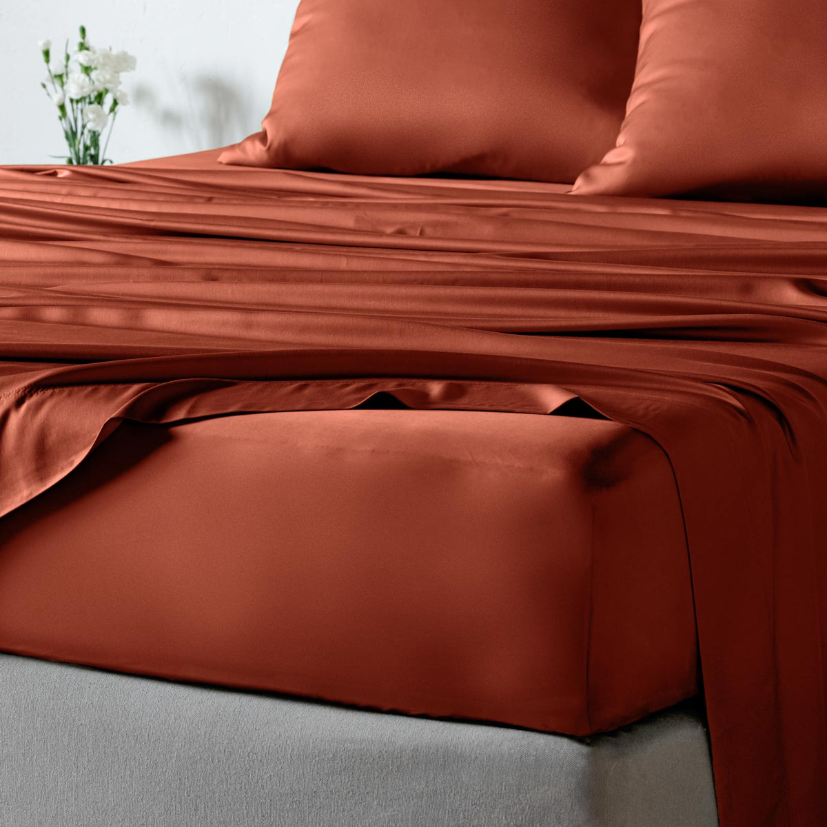 bambaw cozy terracotta fitted sheets and pillows on a bed with a neutral background