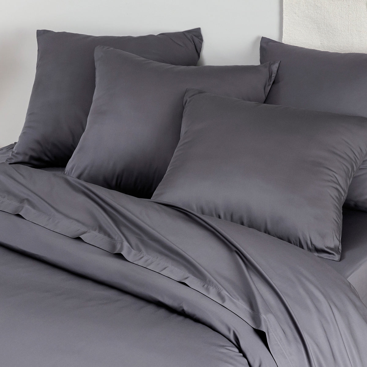 Medium gray bamboo pillowcases pack of 2 on a bed with a pale wall background