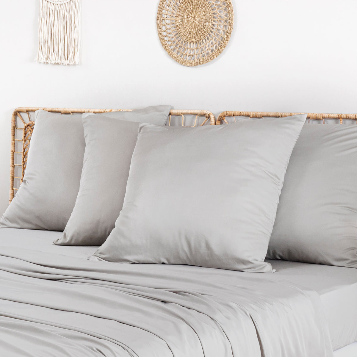 Beige bamboo pillowcases two-pack displayed on a light bed with woven wall decor.
