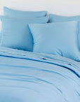 Light blue bamboo pillowcases pack of 2 arranged on a bed with a white headboard and framed print