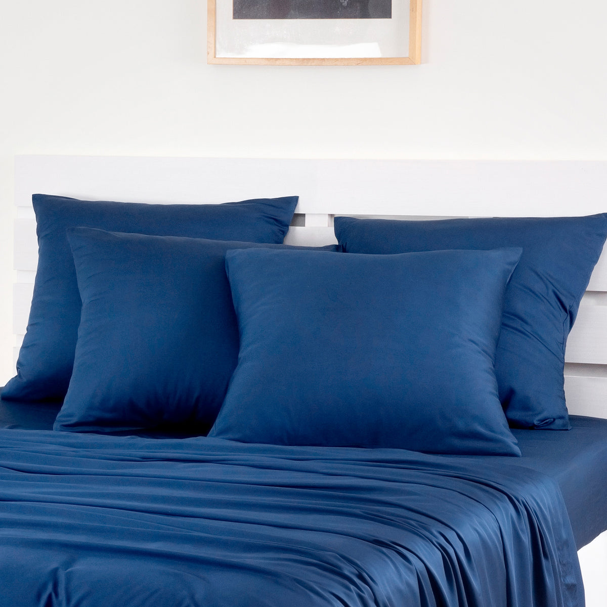 Dark gray bamboo pillowcases pack of 2 layered on a bed against a light wall