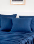 Dark gray bamboo pillowcases pack of 2 layered on a bed against a light wall