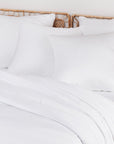 Side view of a bed with white pillows and a wicker headboard in a clean bedroom