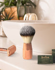 Shaving setup on bathroom counter with copper razor, fluffy brush, and blade boxes