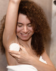 Smiling person in the shower with foam on the arm preparing to shave.