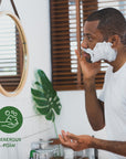 Side profile of a man applying shaving foam to his face at the bathroom sink