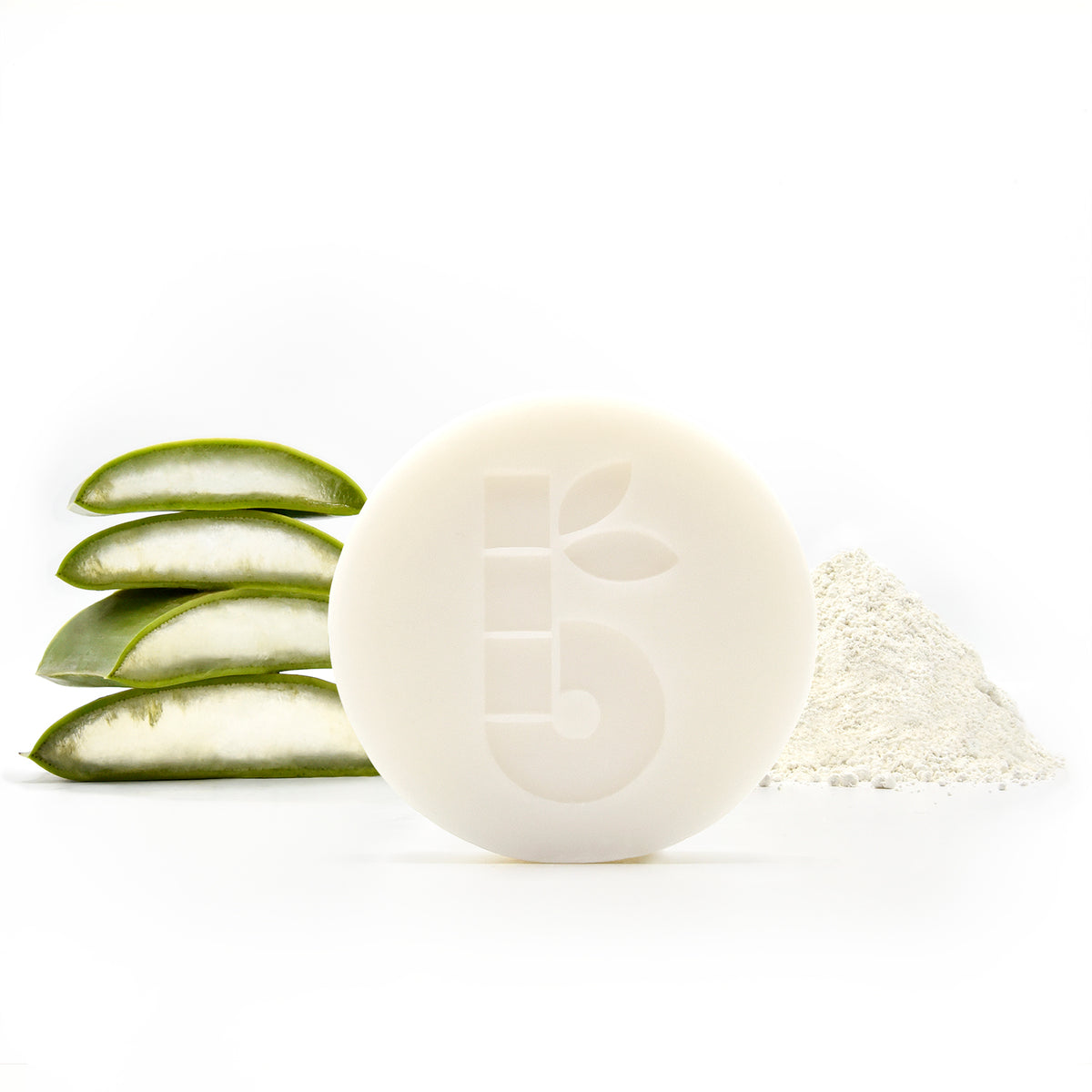 Round white shaving bar with a leaf imprint beside stacked aloe slices and a powder mound