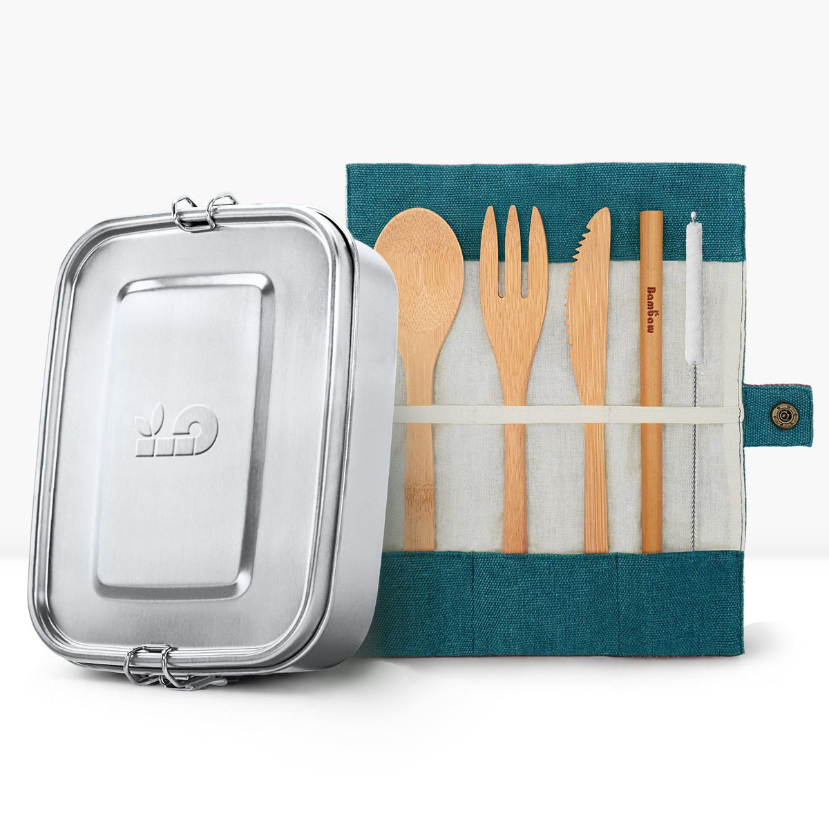 Metal lunch tin beside a teal roll up pouch with wooden spoon fork and knife for a back to school bundle